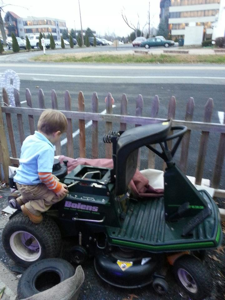 A picture of a young boy on a lawnmower